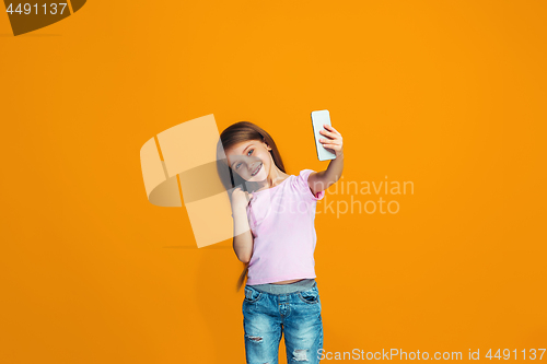 Image of The happy teen girl standing and smiling with phone