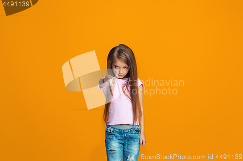 Image of The happy teen girl pointing to you, half length closeup portrait on orange background.