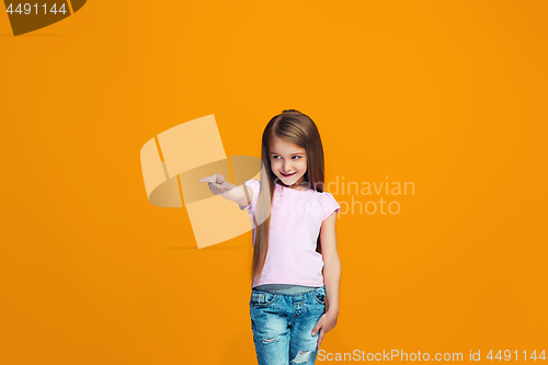 Image of The happy teen girl pointing to you, half length closeup portrait on orange background.