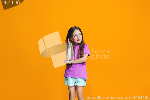 Image of The happy teen girl standing and smiling against orange background.