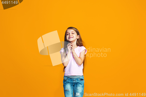 Image of The happy teen girl standing and smiling against orange background.