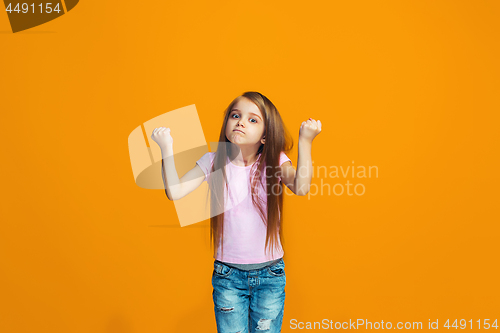 Image of Portrait of angry teen girl on a orange studio background