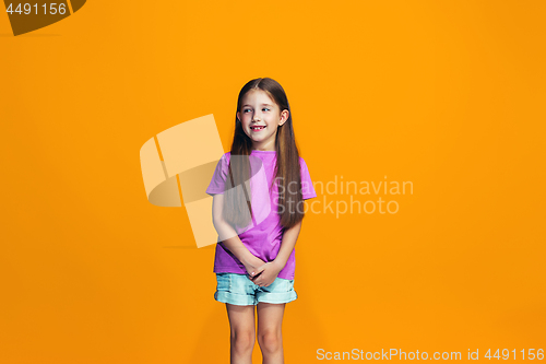 Image of The happy teen girl standing and smiling against orange background.