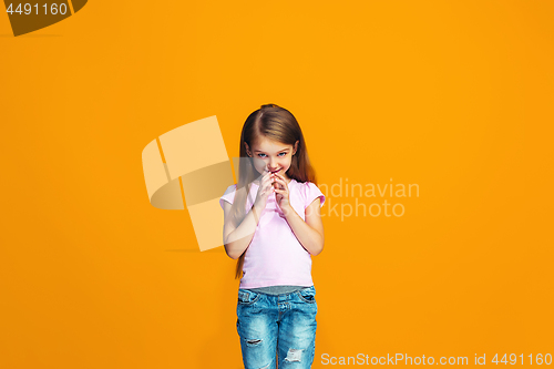 Image of The happy teen girl standing and smiling against orange background.