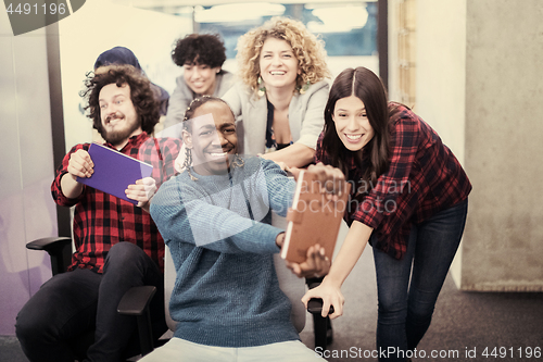 Image of multiethnics business team racing on office chairs