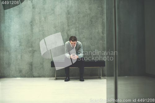 Image of businessman using smart phone while sitting on the bench