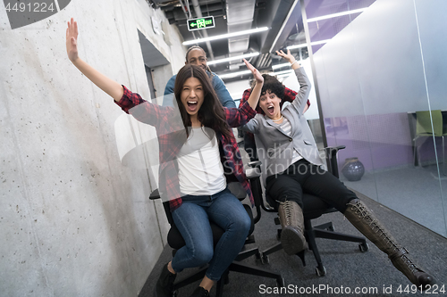 Image of multiethnics business team racing on office chairs