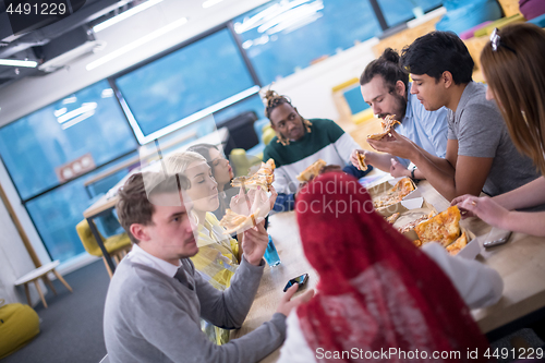 Image of multiethnic business team eating pizza