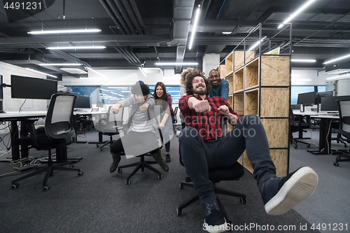 Image of multiethnics business team racing on office chairs