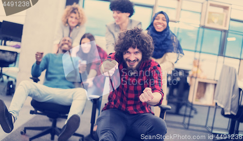 Image of multiethnics business team racing on office chairs