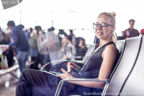 Image of Female traveler using her cell phone while waiting to board a plane at departure gates at asian airport terminal.