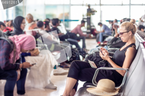 Image of Female traveler using her cell phone while waiting to board a plane at departure gates at asian airport terminal.