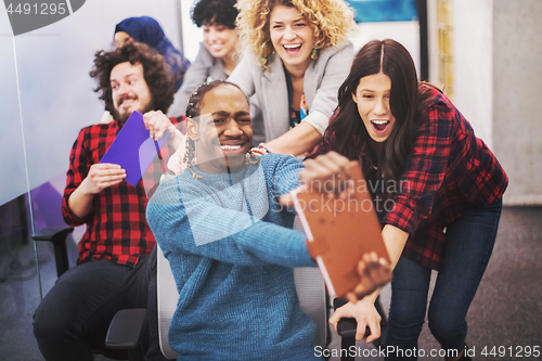 Image of multiethnics business team racing on office chairs