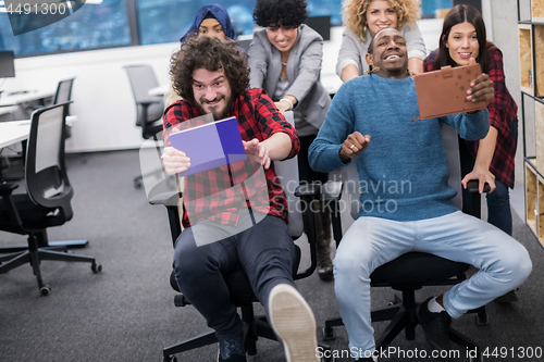 Image of multiethnics business team racing on office chairs