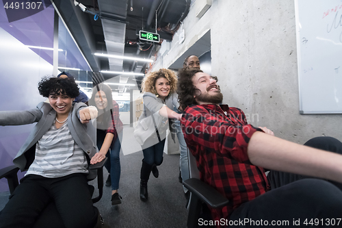 Image of multiethnics business team racing on office chairs