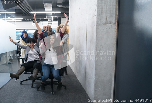 Image of multiethnics business team racing on office chairs