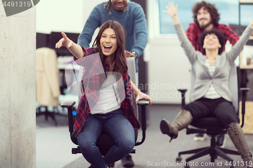 Image of multiethnics business team racing on office chairs