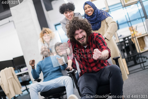 Image of multiethnics business team racing on office chairs