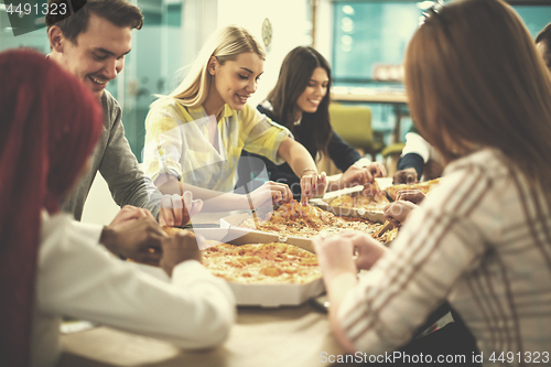 Image of multiethnic business team eating pizza