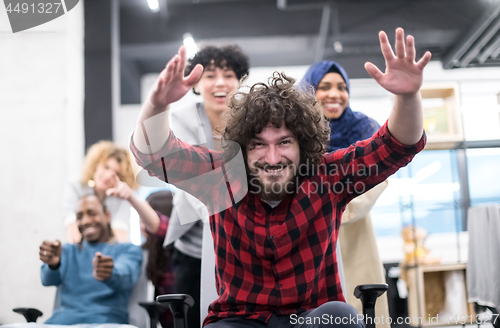 Image of multiethnics business team racing on office chairs