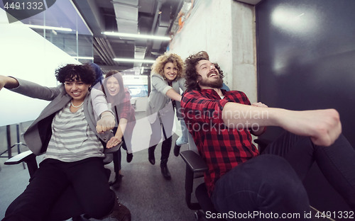 Image of multiethnics business team racing on office chairs