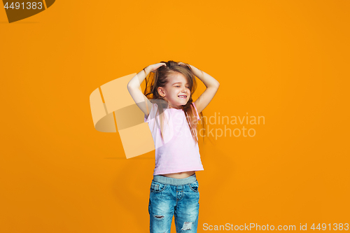 Image of The happy teen girl standing and smiling against orange background.