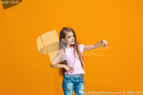 Image of The happy teen girl presenting something, half length closeup portrait on orange background.