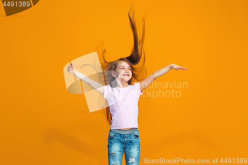 Image of The happy teen girl standing and smiling against orange background.