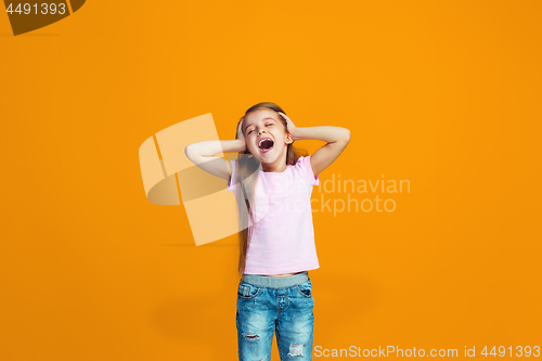 Image of The happy teen girl standing and smiling against orange background.