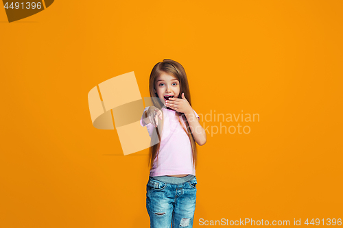 Image of The happy teen girl pointing to you, half length closeup portrait on orange background.