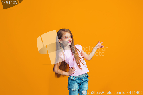 Image of The happy teen girl presenting something, half length closeup portrait on orange background.