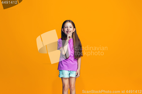 Image of The happy teen girl standing and smiling against orange background.