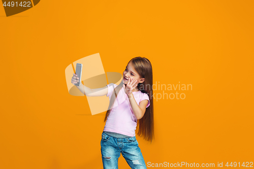 Image of The happy teen girl standing and smiling with phone