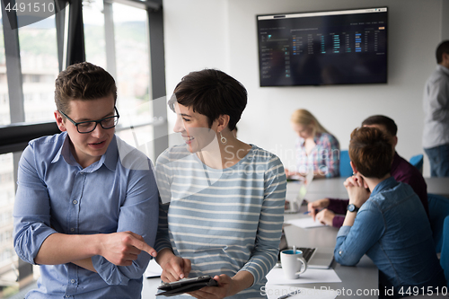 Image of Two Business People Working With Tablet in office