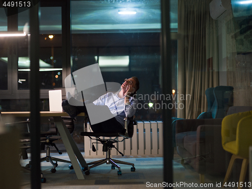 Image of businessman using mobile phone in dark office