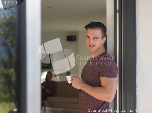 Image of man drinking coffee in front of her luxury home villa