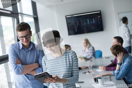 Image of Two Business People Working With Tablet in office