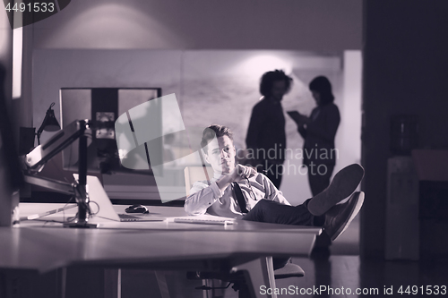 Image of businessman sitting with legs on desk at office