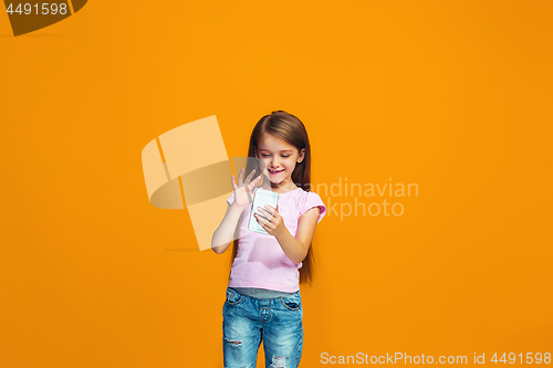Image of The happy teen girl standing and smiling with phone