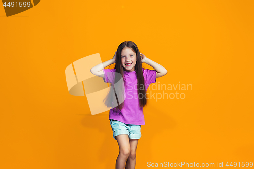 Image of The happy teen girl standing and smiling against orange background.