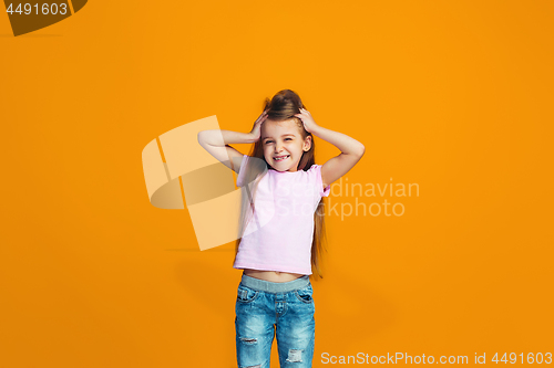 Image of The happy teen girl standing and smiling against orange background.