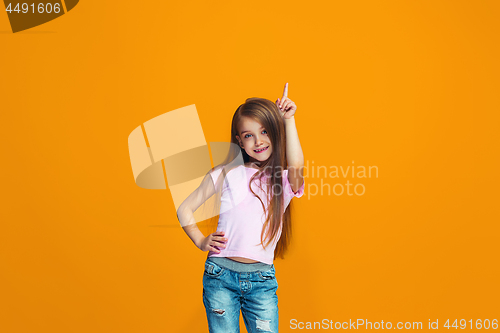 Image of The happy teen girl presenting something, half length closeup portrait on orange background.