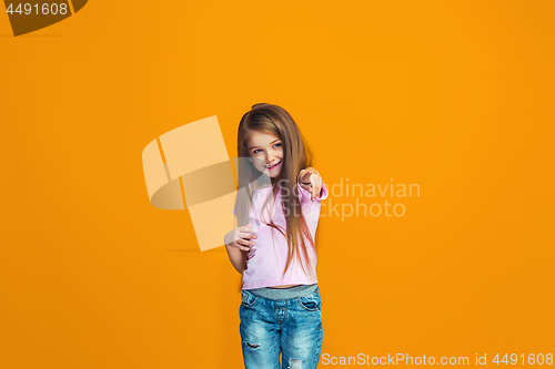 Image of The happy teen girl pointing to you, half length closeup portrait on orange background.