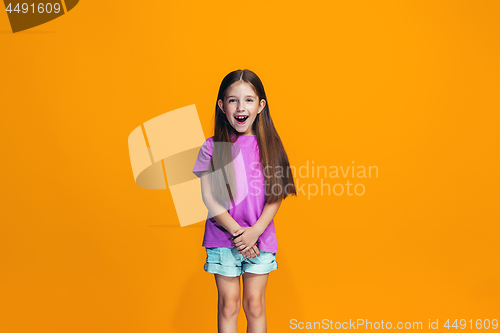 Image of The happy teen girl standing and smiling against orange background.