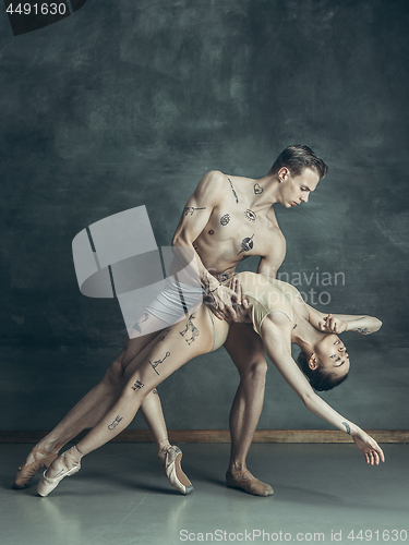 Image of The young modern ballet dancers posing on gray studio background