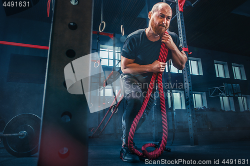 Image of Men with battle rope battle ropes exercise in the fitness gym. CrossFit.