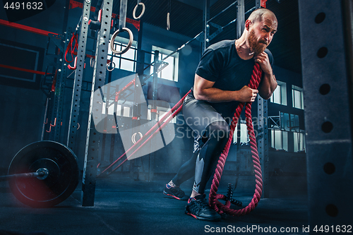 Image of Men with battle rope battle ropes exercise in the fitness gym. CrossFit.