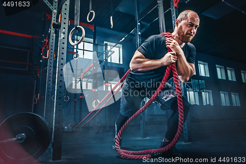 Image of Men with battle rope battle ropes exercise in the fitness gym. CrossFit.