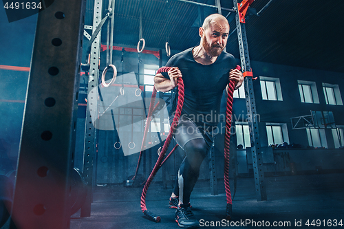 Image of Men with battle rope battle ropes exercise in the fitness gym. CrossFit.