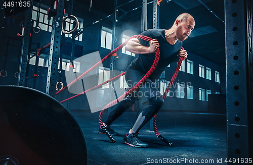 Image of Men with battle rope battle ropes exercise in the fitness gym. CrossFit.